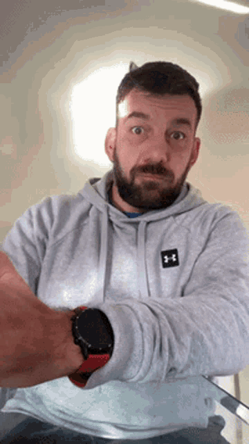 a man with a beard wears a grey under armour sweatshirt