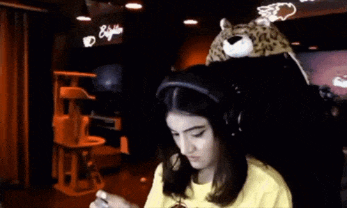 a woman wearing headphones and a leopard hat is looking at the camera .
