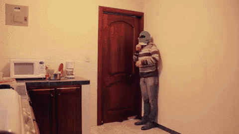 a man with a green mask on his face stands in a kitchen