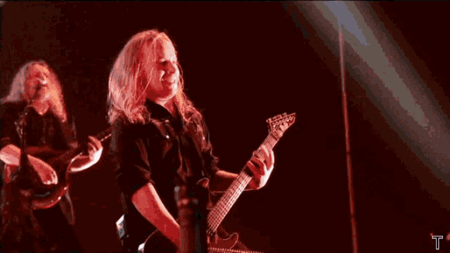 a man plays a guitar while a woman sings in front of a crowd