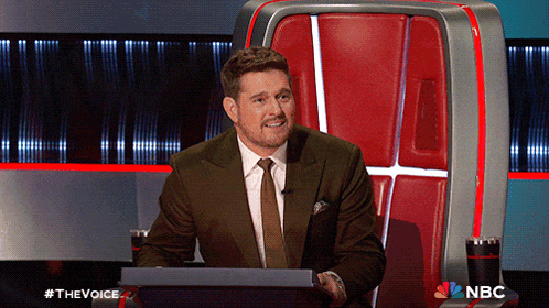 a man in a suit and tie is sitting in front of a podium with the nbc logo on it