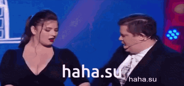 a man in a tuxedo and a woman in a black dress are on a stage with the website haha.su in the background