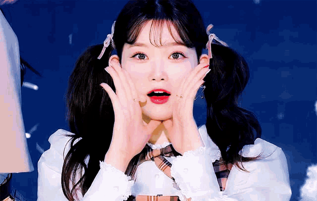 a girl with pigtails is making a surprised face with her hands on her face