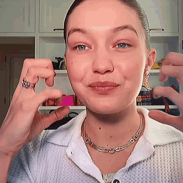 a close up of a woman 's face with a necklace and a ring on her finger