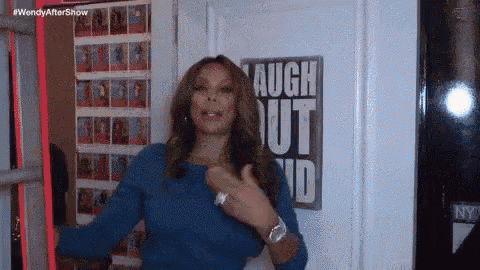 a woman in a blue shirt is standing in front of a sign that says laugh out loud