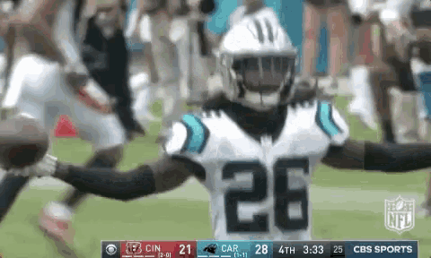 a football player with the number 26 on his jersey is holding a football in his hands .