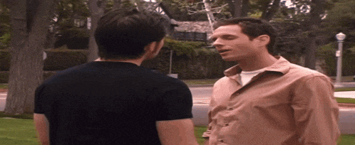 two men are standing next to each other in front of a street light