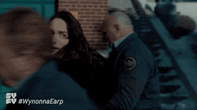 a man and woman are fighting in front of a stop sign