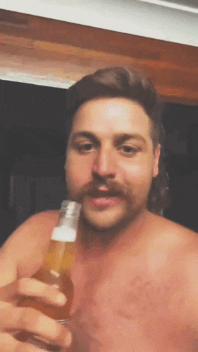 a shirtless man with a mustache is holding a bottle of beer .