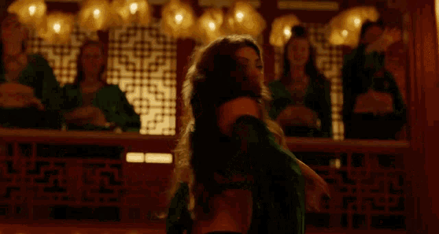 a woman in a green bikini is dancing in front of a group of people
