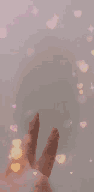 a person 's hand is making a peace sign surrounded by pink bubbles and stars