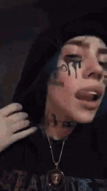 a girl with blue hair is wearing a hoodie and a necklace .