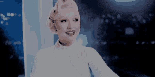 a woman in a white dress is smiling in a pixelated video .