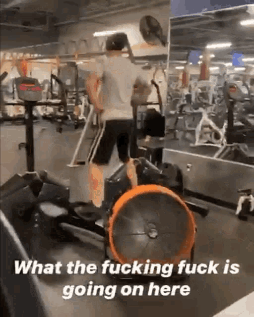 a man is riding an elliptical in a gym with the caption what the fucking fuck is going on here .