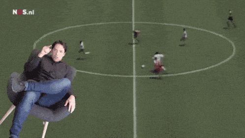 a man sitting in a chair on a soccer field with the words he 's good though