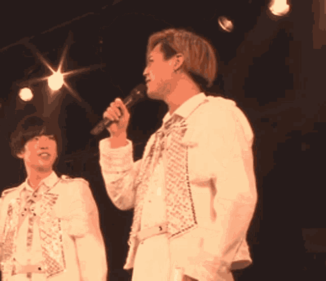 a woman in a white dress is singing into a microphone on stage
