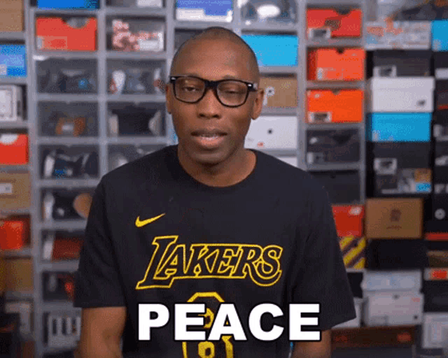 a man wearing glasses and a black lakers shirt says peace