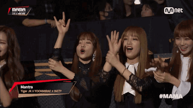 a group of women are sitting in a stadium with mantra written on the screen