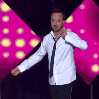 a man in a white shirt and black tie is dancing on a stage .