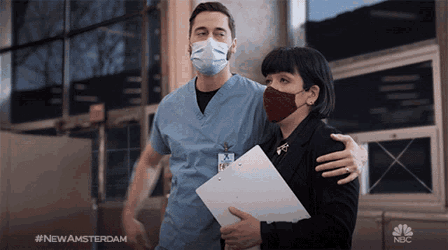 a man wearing a mask is hugging a woman wearing a red mask