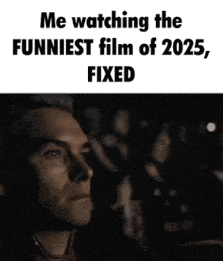a man is sitting in a dark room watching a funny movie .