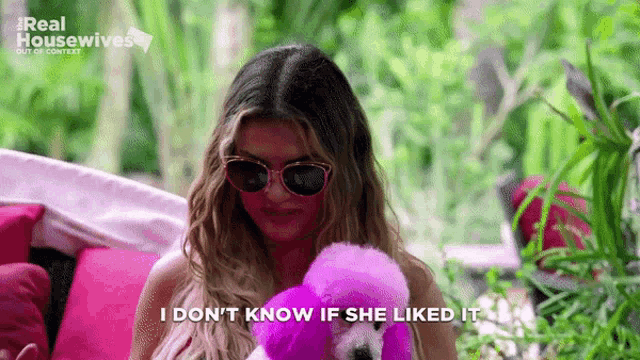 a woman wearing sunglasses is holding a pink flamingo and says `` i don t know if she liked it ''
