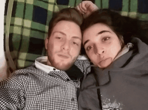a man and a woman are posing for a picture together while laying on a bed .