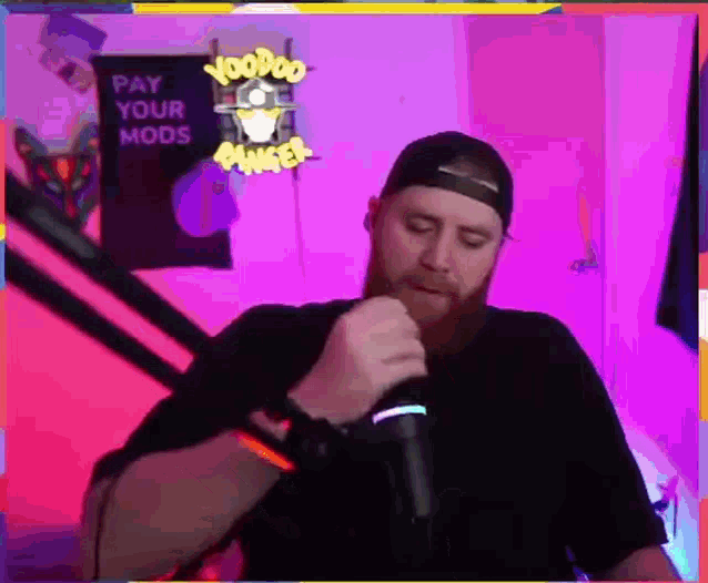 a man singing into a microphone in front of a sign that says voodoo
