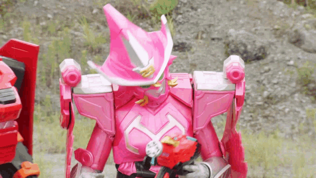 a pink robot with a sword and shield is holding a red object .