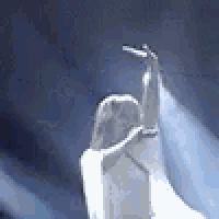 a statue of a woman in a white dress is standing in front of a blue light .