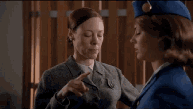 two women in blue uniforms are standing next to each other in a room .