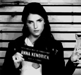 a black and white photo of a woman holding a sign that says " anna kendrick "