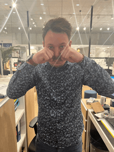a man in a floral shirt is making a face with his hands