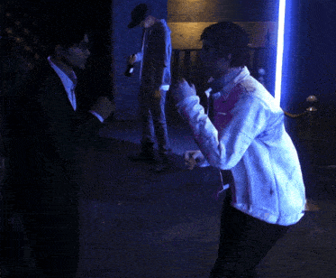a man in a white jacket is standing next to another man in a suit