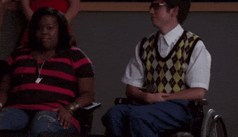 a man in a plaid vest is holding a woman in a wheelchair 's hand