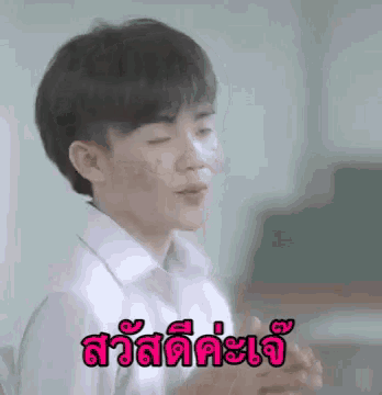 a young boy in a white shirt is making a funny face in a classroom with a foreign language .