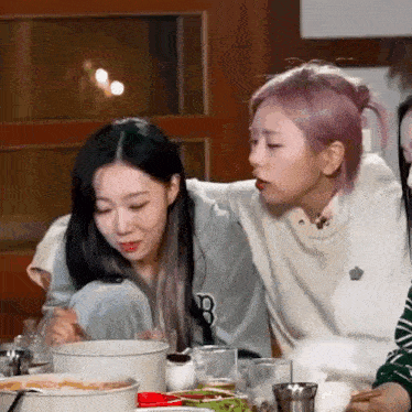 two girls are sitting at a table eating food and drinking .