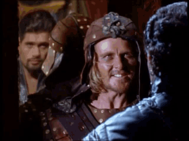 a man wearing a leather helmet is smiling in front of two other men