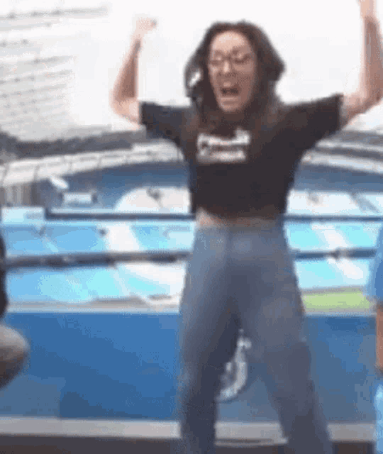 a woman in a crop top and jeans is standing with her arms in the air