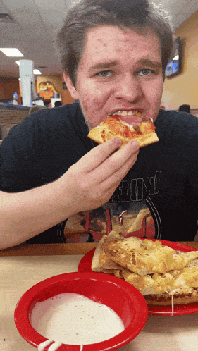 a man wearing a black shirt that says floyd is eating a pizza