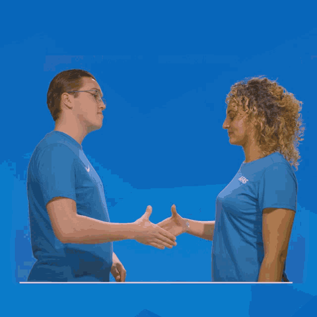 a man and a woman are shaking hands and the man is wearing a shirt that says asics