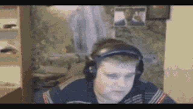 a young man wearing headphones is sitting in front of a computer screen .