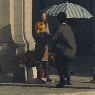 a man holding a striped umbrella walks down a sidewalk next to a woman