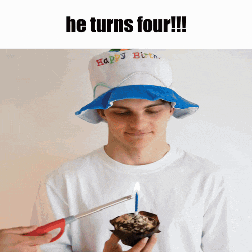 a man wearing a hat that says happy birthday is cutting a candle out of a muffin