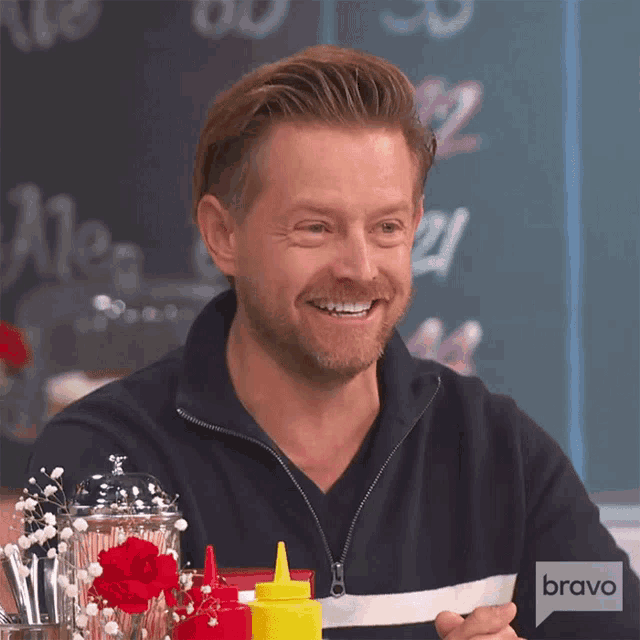 a man is smiling and holding a piece of paper with bravo written on it