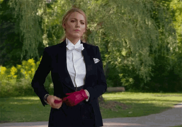 a woman in a tuxedo and bow tie holds a red glove