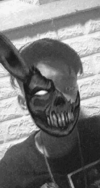 a black and white photo of a man wearing a skull mask .