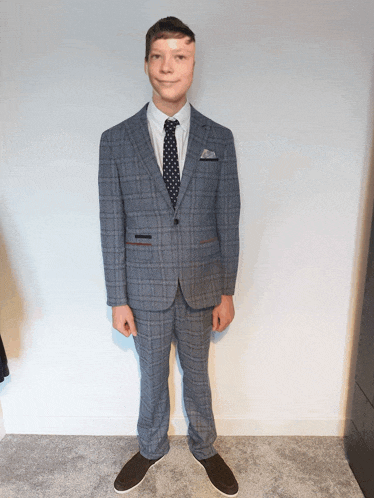 a man in a suit and tie is standing in front of a white wall
