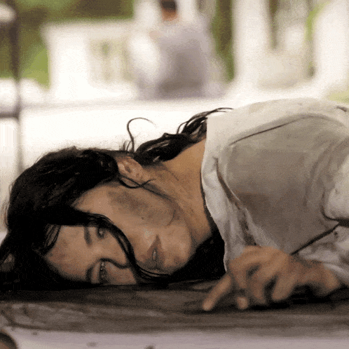 a woman in a white shirt is laying on the ground with a brush in her hand