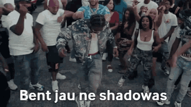 a man is dancing in front of a crowd of people with the words bent jau ne shadowas on the bottom .